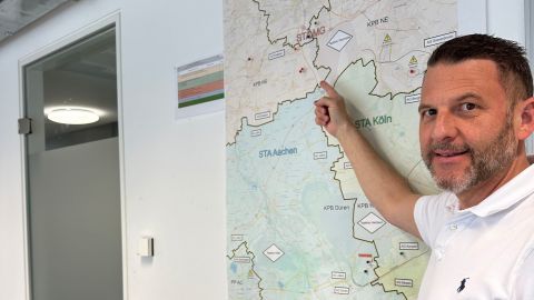 Detective Chief Inspector Alexander Maaßen points his finger at a map hanging on the wall in an office.