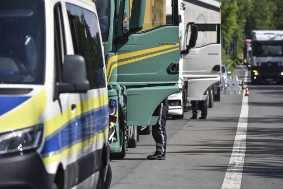 Kontrollstelle: Hinter einem Polizeifahrzeug stehen mehrere Lkw mit geöffneten Fahrertüren