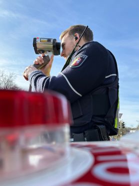 Ein Polizist misst die Geschwindigkeit von Autofahrern mit einem Lasermessgerät.