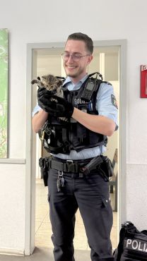 Ein Polizeibeamter hält eine Babykatze hoch. 